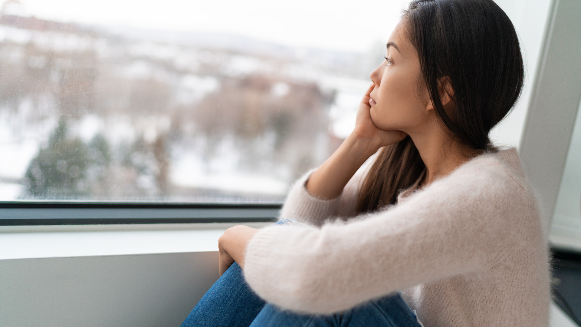 Mujer triste mirando por una ventana con expresión de melancolía, representando la duda emocional en una relación. Reflexión sobre el amor y la conexión en pareja, disponible en Micentrolasrozas.es.