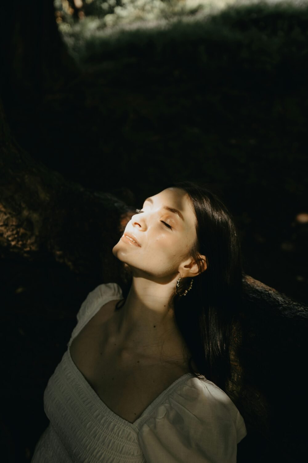 Mujer respirando profundamente con una luz solar apuntando a su cara