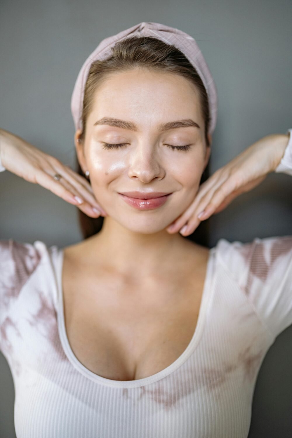 Mujer masajeandose la cara satisfactoriamente, yoga facial en casa