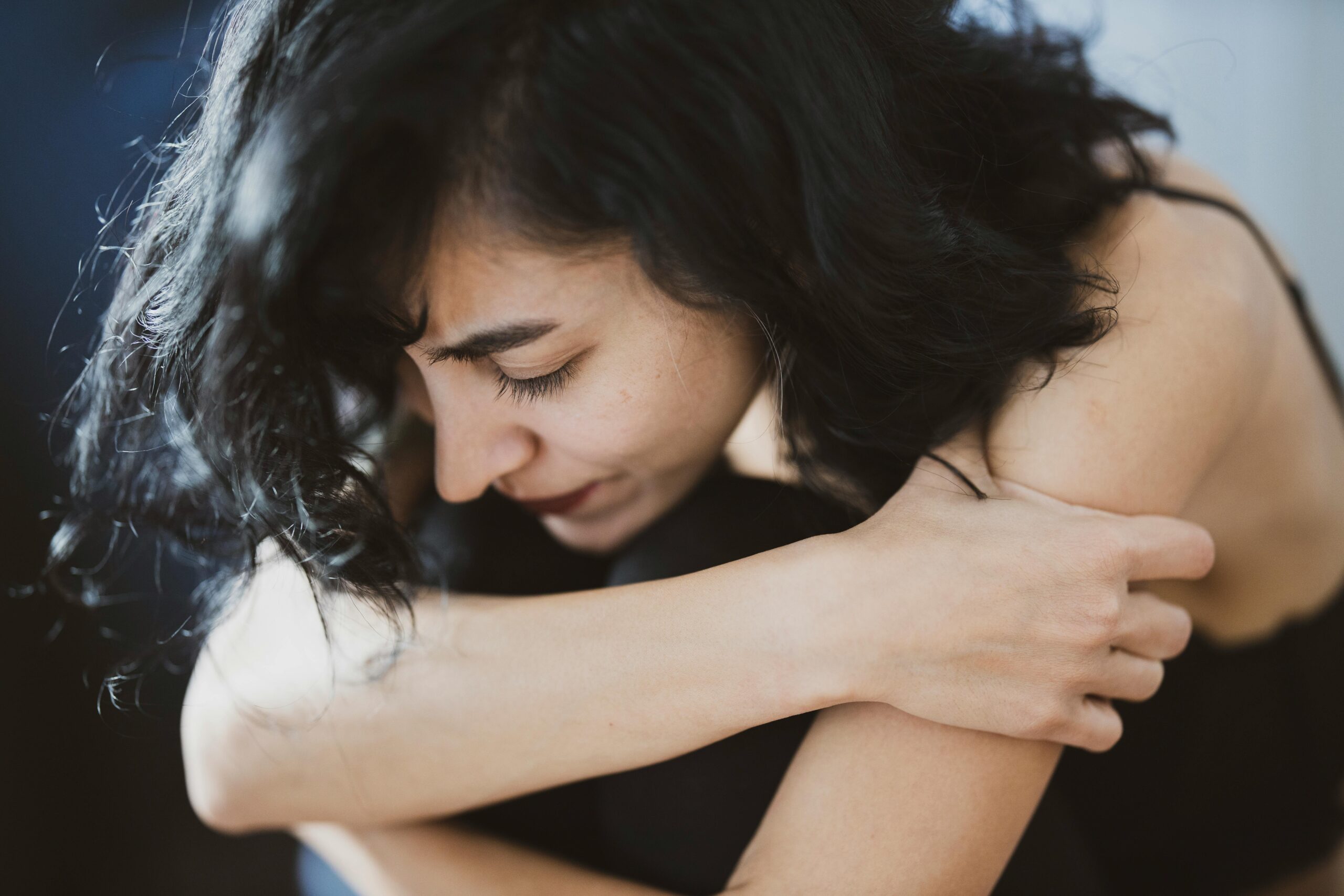 Mujer abrazándose a sí misma con expresión de ansiedad y angustia emocional
