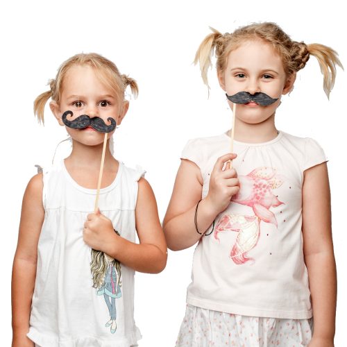 Two cute little girls with paper mustaches while posing against white background